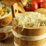 Sauerkraut in a wooden barrel and cabbage soup in the background